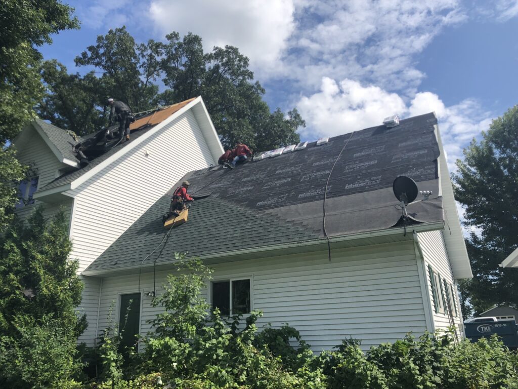 Roofers with safety ropes on a steep two-story roof on Smith Lake near Osakis, MN